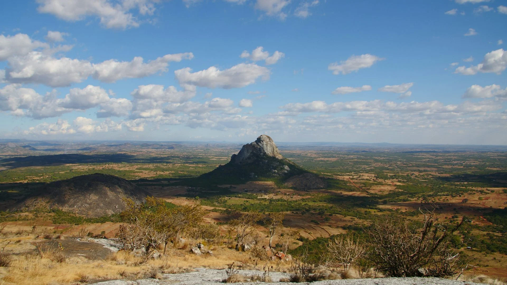 A large mountain of bare rock rises from an otherwise mostly flat landscape.