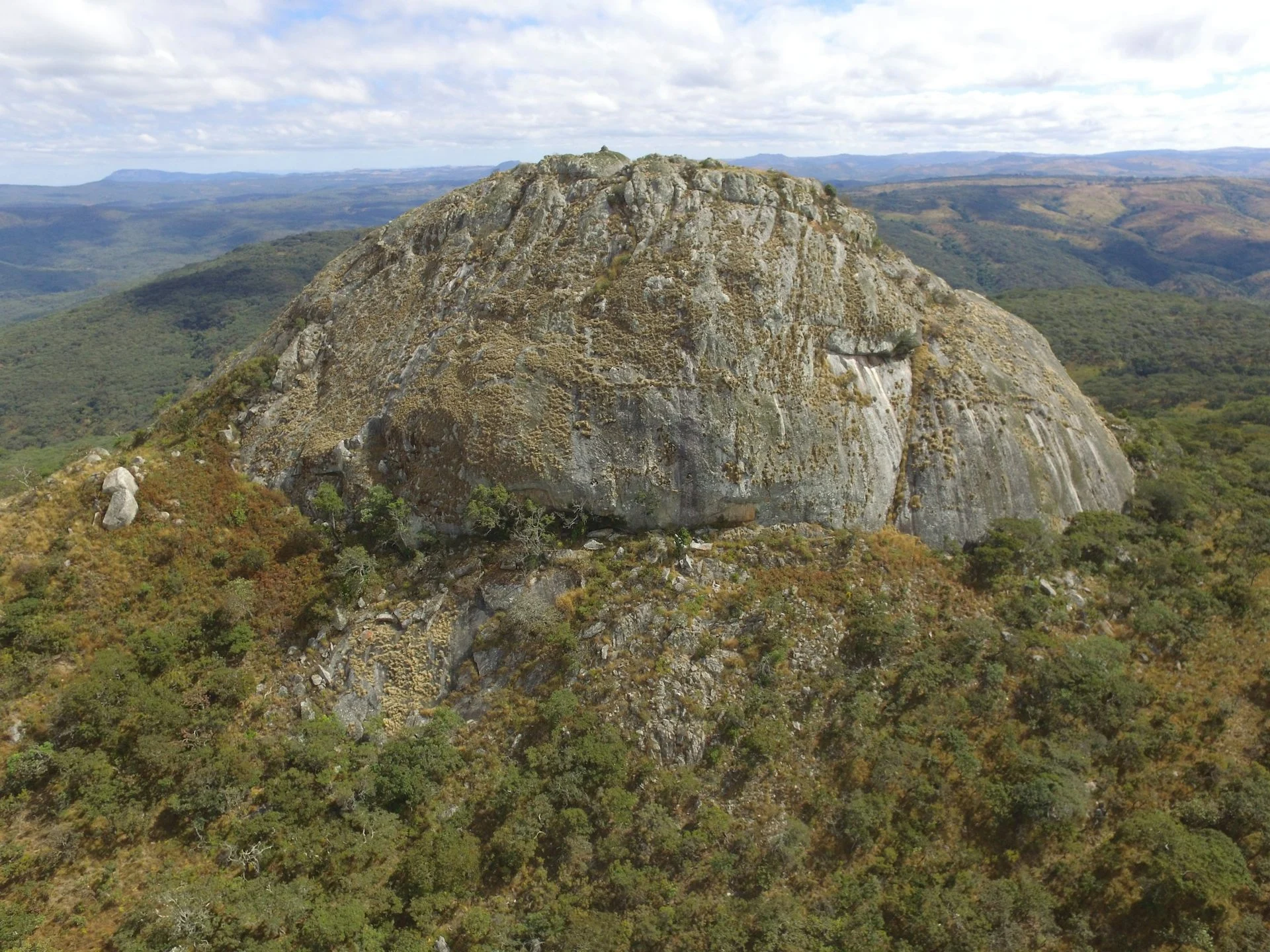A large rock outcrop on a high meadow, surrounded by trees